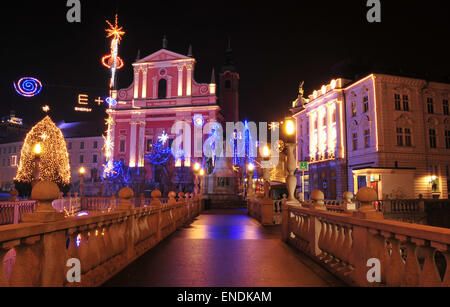 Uno dei Ljubljanas tre ponti con la santa chiesa francescana in background, decorato per il Natale e il Capodanno Vacanze Foto Stock