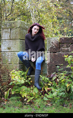Una bella donna seduta in un parco che indossa in autunno Foto Stock