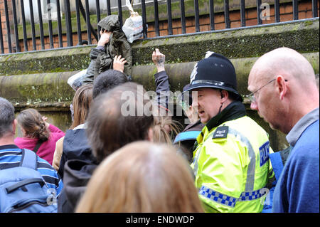 Liverpool, Regno Unito. Il 3 maggio, 2015. Durante una dimostrazione dai sostenitori della professione, alimenti e bevande è passata attraverso le ringhiere per gli attivisti rimanendo all'interno dell'ex edificio della banca. Esse sono state occupando a partire dal mese di aprile 18th, e hanno usato l edificio per senzatetto e gente di strada, dando loro riparo e cibo. L'edificio precedentemente era stato lasciato vuoto per 11 anni. Un Merseyside sergente di polizia guarda impotente come più cibo e i materiali di consumo sono passati per gli attivisti ancora all'interno della ex banca di credito locali: David Colbran/Alamy Live News Foto Stock