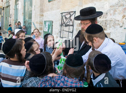 Ultra un ebreo ortodosso uomo distribuendo cibo ai bambini poveri di Gerusalemme in Israele Foto Stock