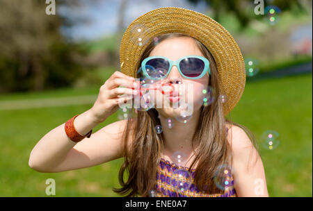 Una bambina facendo bolle di sapone in natura Foto Stock