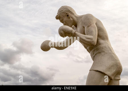 Statua virile boxer con guanti sferrare pugni a nuvole Foto Stock