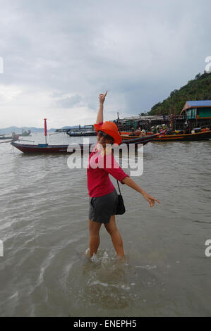 Donna Thai giocando sulla spiaggia al villaggio di pescatori di Koh Isola Phithak durante la tempesta di pioggia in Lang Suan, Chumphon Thailandia. Foto Stock