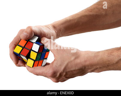 L'uomo la torsione di un cubo di Rubik puzzle con colori codificati Foto Stock