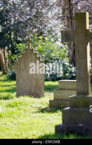 Un vecchio edificio merlato lapide in un cimitero rurale inondata di sole di primavera. Foto Stock