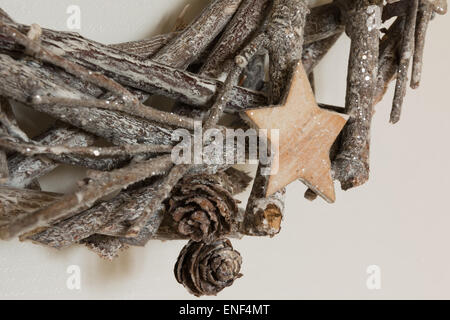 Rami intrecciati tra loro decorazione di Natale con la stella di legno e un po' di pigne Foto Stock