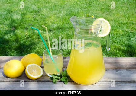 La limonata e limone su legno isolato su erba verde sullo sfondo Foto Stock