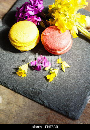Amaretti colorati e i primi fiori di primavera sulla vecchia sullo sfondo di legno Foto Stock