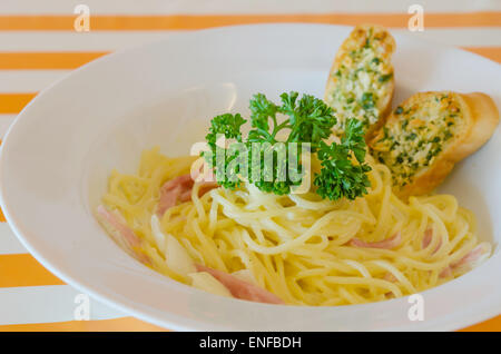 Spaghetti alla carbonara con lardo e aglio pane sul piatto Foto Stock