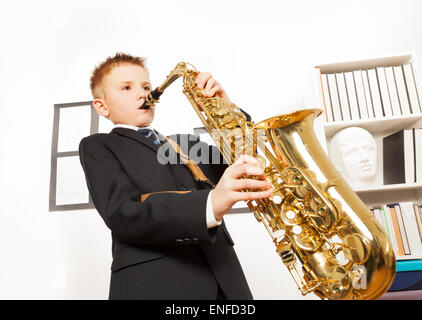 Ragazzo in uniforme scolastica giocando su alto sassofono Foto Stock