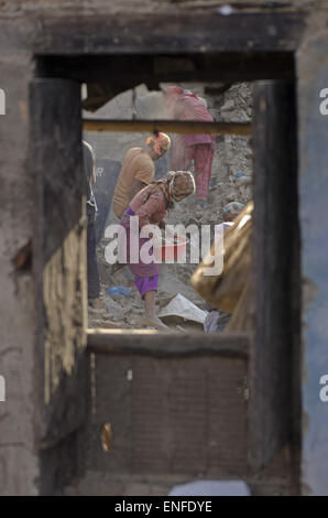 Bhaktapur, Nepal. Xxv Aprile, 2015. Una donna di pulizia dei detriti di casa sua per raccogliere i suoi averi dopo la casa è crollato da la settimana scorsa il terremoto mortale in Nepal. Una delle principali 7.9 terremoto ha colpito Kathmandu a metà giornata di sabato 25 aprile, ed è stata seguita da più scosse di assestamento che ha attivato le valanghe su Mt. Everest che seppellì gli alpinisti nei loro campi base. Molte case, palazzi e templi della capitale erano distrutti durante il terremoto, lasciando oltre 7000 morti e molti più intrappolato sotto i detriti come emergenza soccorritori tentativo di rimozione dei detriti e trovare superstiti. R Foto Stock