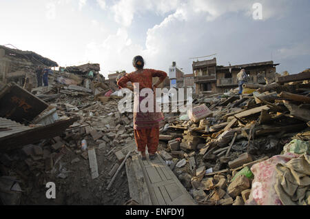 Bhaktapur, Nepal. Xxv Aprile, 2015. Una donna si affaccia sulla sua casa di Bhaktapur che era crollato a causa della scorsa settimana terremoto mortale in Nepal. Una delle principali 7.9 terremoto ha colpito Kathmandu a metà giornata di sabato 25 aprile, ed è stata seguita da più scosse di assestamento che ha attivato le valanghe su Mt. Everest che seppellì gli alpinisti nei loro campi base. Molte case, palazzi e templi della capitale erano distrutti durante il terremoto, lasciando oltre 7000 morti e molti più intrappolato sotto i detriti come emergenza soccorritori tentativo di rimozione dei detriti e trovare superstiti. Regolare scosse di assestamento hanno ostacolare Foto Stock