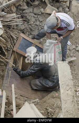 Bhaktapur, Nepal. Xxv Aprile, 2015. Un uomo di recuperare i suoi beni da un ripiano in legno che è stata sepolta sotto i detriti dall'edificio caduto dopo la settimana scorsa il terremoto mortale in Nepal. Una delle principali 7.9 terremoto ha colpito Kathmandu a metà giornata di sabato 25 aprile, ed è stata seguita da più scosse di assestamento che ha attivato le valanghe su Mt. Everest che seppellì gli alpinisti nei loro campi base. Molte case, palazzi e templi della capitale erano distrutti durante il terremoto, lasciando oltre 7000 morti e molti più intrappolato sotto i detriti come emergenza soccorritori tentare di cancellare i detriti Foto Stock