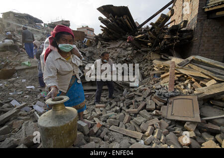 Bhaktapur, Nepal. Xxv Aprile, 2015. Una donna che recupera la sua Ã"Gagri', un tradizionale pentola di acqua sotto le macerie della sua casa caduti a causa della scorsa settimana terremoto mortale in Nepal. Una delle principali 7.9 terremoto ha colpito Kathmandu a metà giornata di sabato 25 aprile, ed è stata seguita da più scosse di assestamento che ha attivato le valanghe su Mt. Everest che seppellì gli alpinisti nei loro campi base. Molte case, palazzi e templi della capitale erano distrutti durante il terremoto, lasciando oltre 7000 morti e molti più intrappolato sotto i detriti come emergenza soccorritori tentativo di rimozione dei detriti e trovare superstiti. Foto Stock