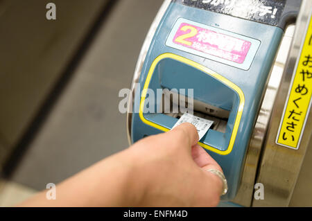 Mano inserire un biglietto del treno in ticket gate/tornello in Giappone. Automazione di giapponese. Foto Stock