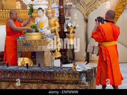 I monaci di mettere acqua su una statua in Shwedagon pagoda Yangon, Myanmar Foto Stock