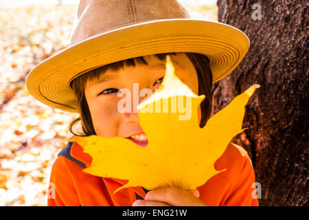 Close up di sorridere razza mista boy holding autumn leaf Foto Stock