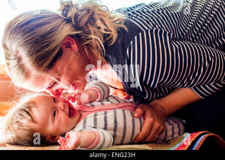 Sorridente madre caucasica cullano Baby girl Foto Stock