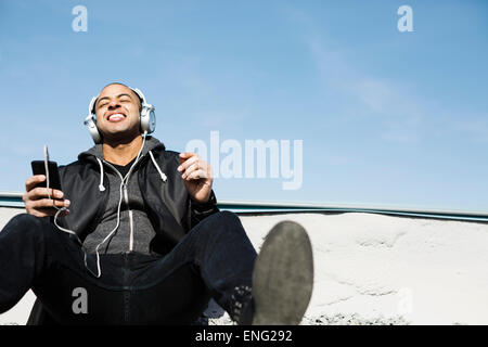 Razza mista uomo che ascolta le cuffie sulla spiaggia Foto Stock