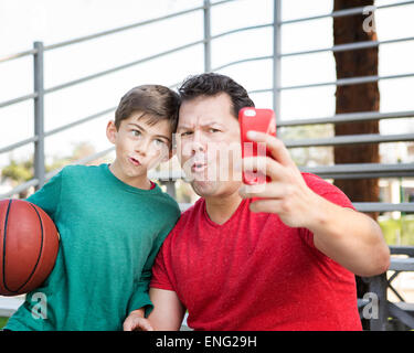 Caucasian padre e figlio tenendo il telefono cellulare ancora sulle gradinate Foto Stock