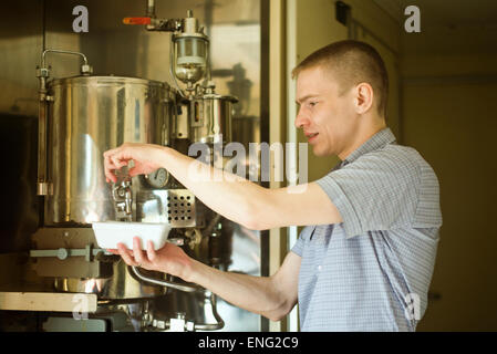 Uomo caucasico versando acqua calda nel recipiente Foto Stock