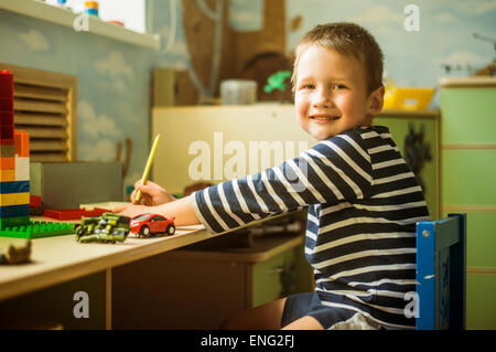 Ragazzo caucasico pittura alla scrivania in sala giochi Foto Stock