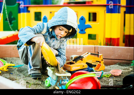 Ragazzo caucasico giocando in sandbox Foto Stock