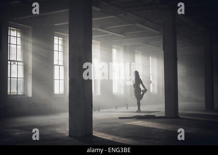 Nero donna stretching in palestra scuro Foto Stock