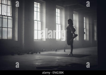 Nero donna stretching in palestra scuro Foto Stock