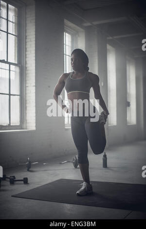 Nero donna stretching in palestra scuro Foto Stock