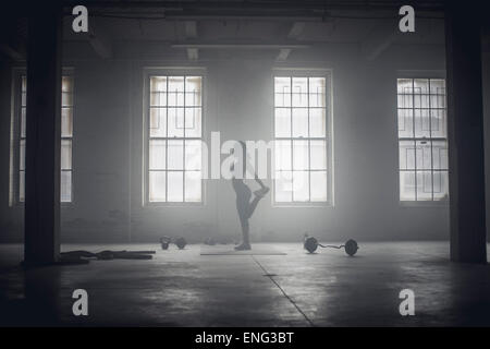 Nero donna stretching in palestra scuro Foto Stock