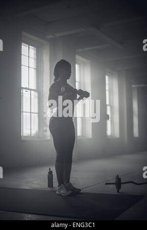 Nero donna sollevamento pesi nella palestra scuro Foto Stock