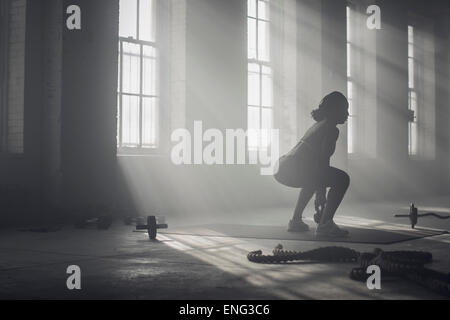 Nero donna sollevamento pesi nella palestra scuro Foto Stock