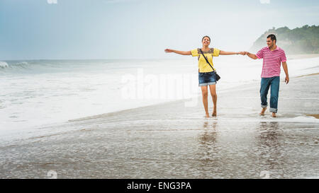 Coppia ispanica giocando in onde sulla spiaggia Foto Stock