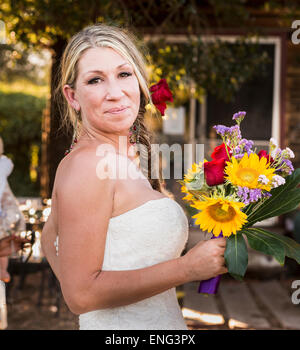 Sorridente sposa caucasica holding bouquet di fiori Foto Stock