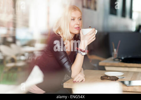 Donna di bere tazza di caffè nella caffetteria Foto Stock