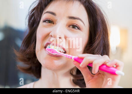 Close up donna ispanica spazzolare i suoi denti Foto Stock