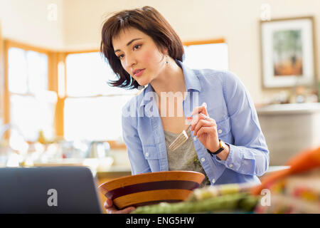 Ispanico titolare di azienda di mangiare insalata in home office Foto Stock