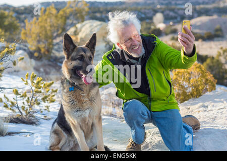 Uomo anziano tenendo cellulare fotografia con il cane sulle formazioni rocciose Foto Stock