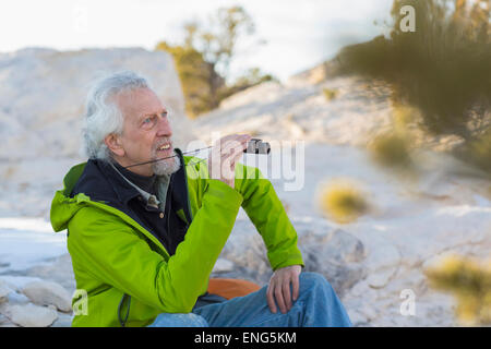 Uomo vecchio ammirando vista con il binocolo Foto Stock