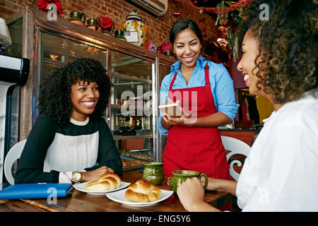Cameriera serve clienti in cafe Foto Stock