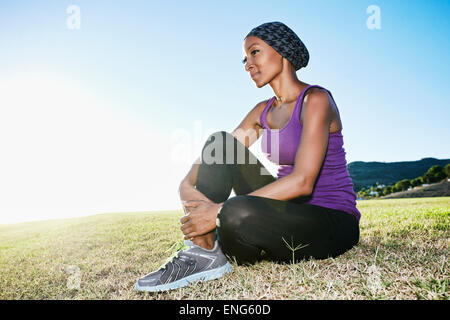 African American donna seduta su un prato in posizione di parcheggio Foto Stock