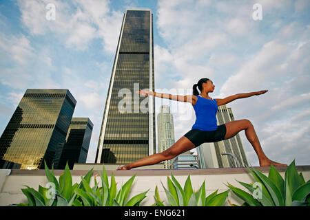 African American donna a praticare yoga sul tetto urbano Foto Stock