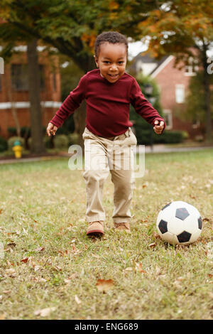 African American boy che giocano a calcio in posizione di parcheggio Foto Stock