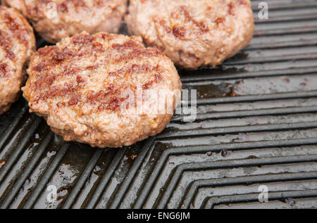 Hamburger di manzo cottura su una piastra di metallo Foto Stock