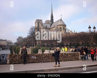 I turisti presso il famoso ponte del lucchetto di Parigi con la cattedrale di Notre Dame in background Foto Stock