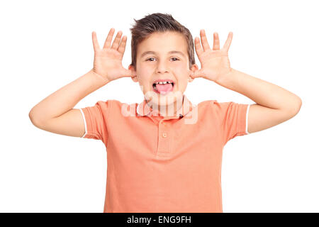 Poco capretto maschio facendo una faccia e attaccando la sua lingua fuori isolati su sfondo bianco Foto Stock