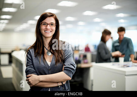 Una donna con i bracci ripiegati sorridente. Foto Stock