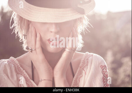 Outdoor Ritratto di giovane donna la cui faccia è parzialmente nascosto da un cappello Foto Stock