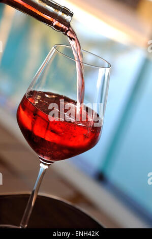 Rosé che versa un bicchiere di vino rosa chiaro nella soleggiata terrazza estiva Foto Stock